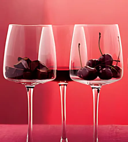 Trois verres de vin avec des cerises noires illustrant les caractéristiques du Cabernet Sauvignon